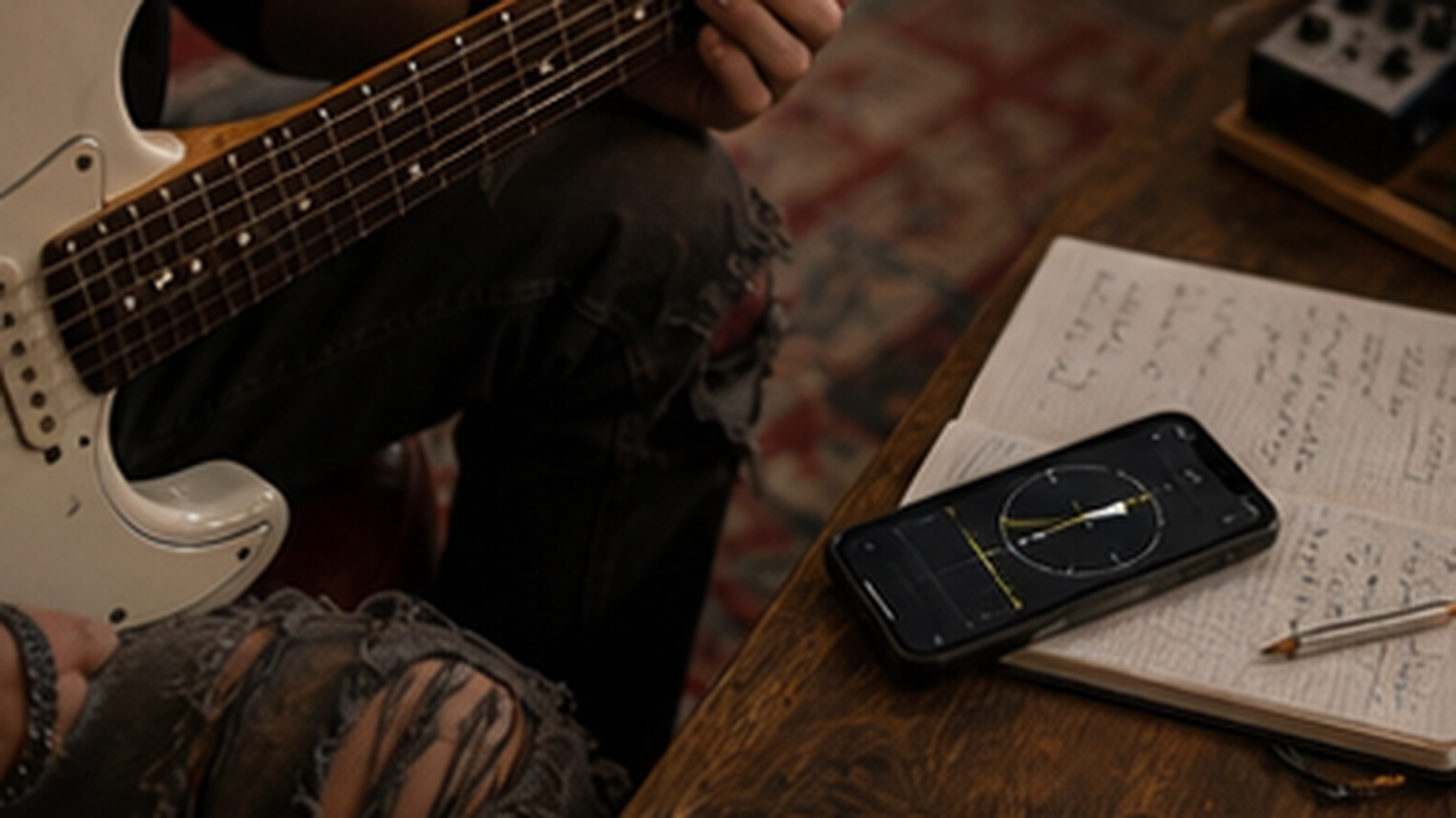 Guitar in a quiet warm-up with a phone tuner and handwritten session notes nearby